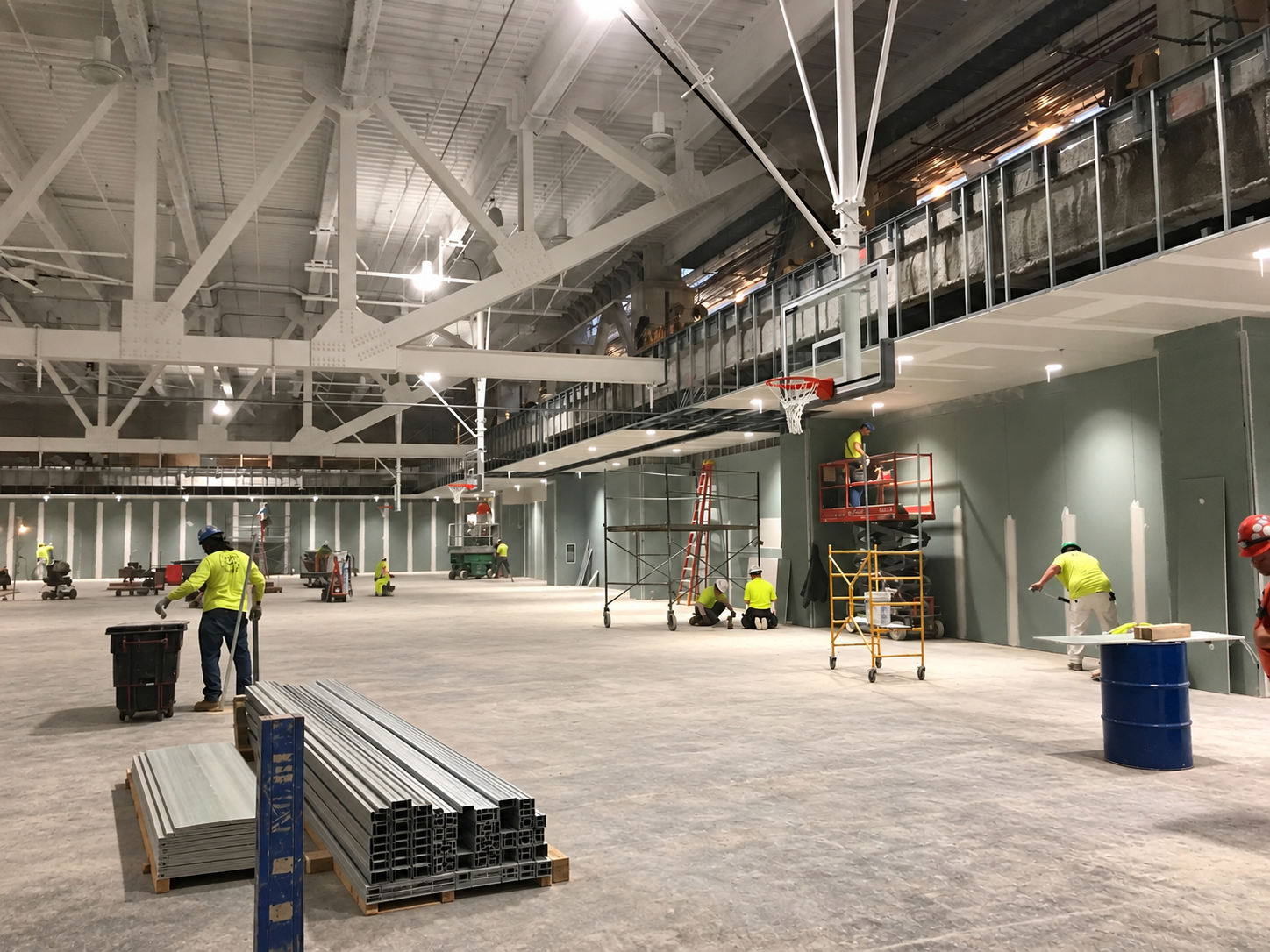 Gymnasium under construction with exposed framing and basketball hoops